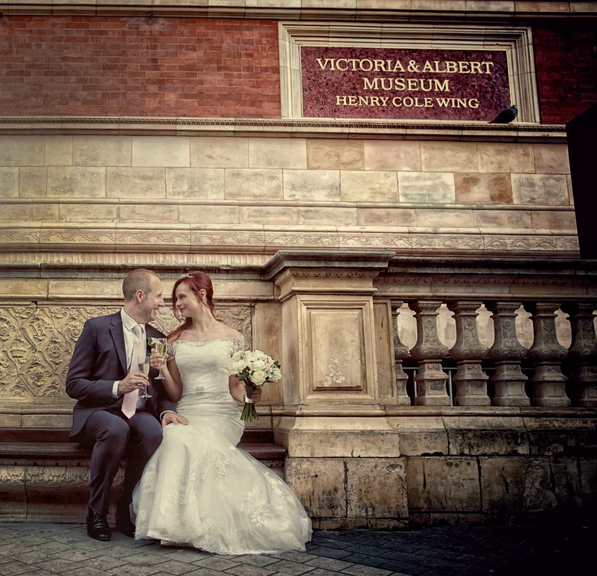 Wedding couple toast on bench outside Victoria and Albert Museum