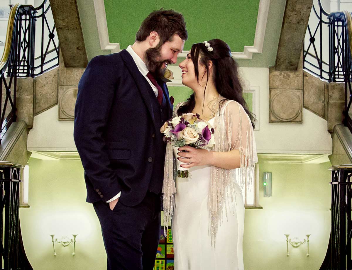 Couple smile on stairs inside for Islington Town Hall wedding photographer