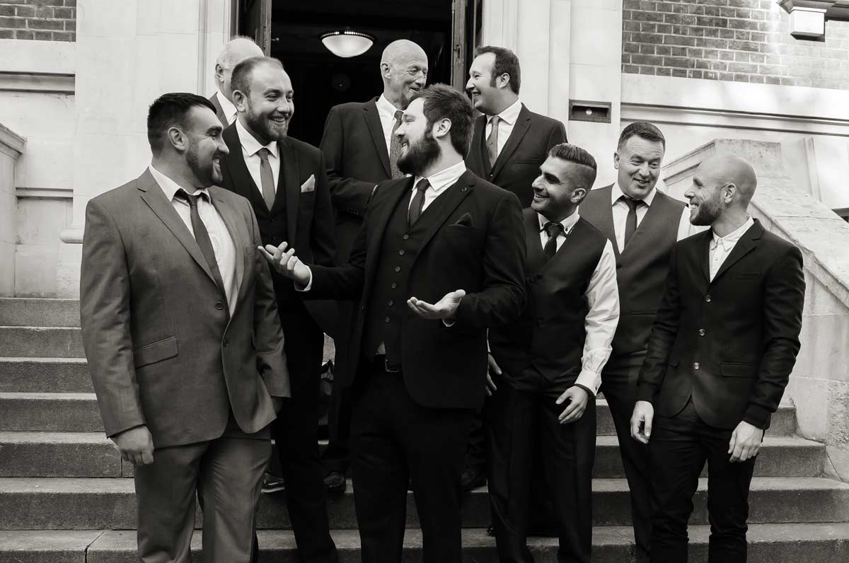 Groomsmen chat on the steps of Islington town hall