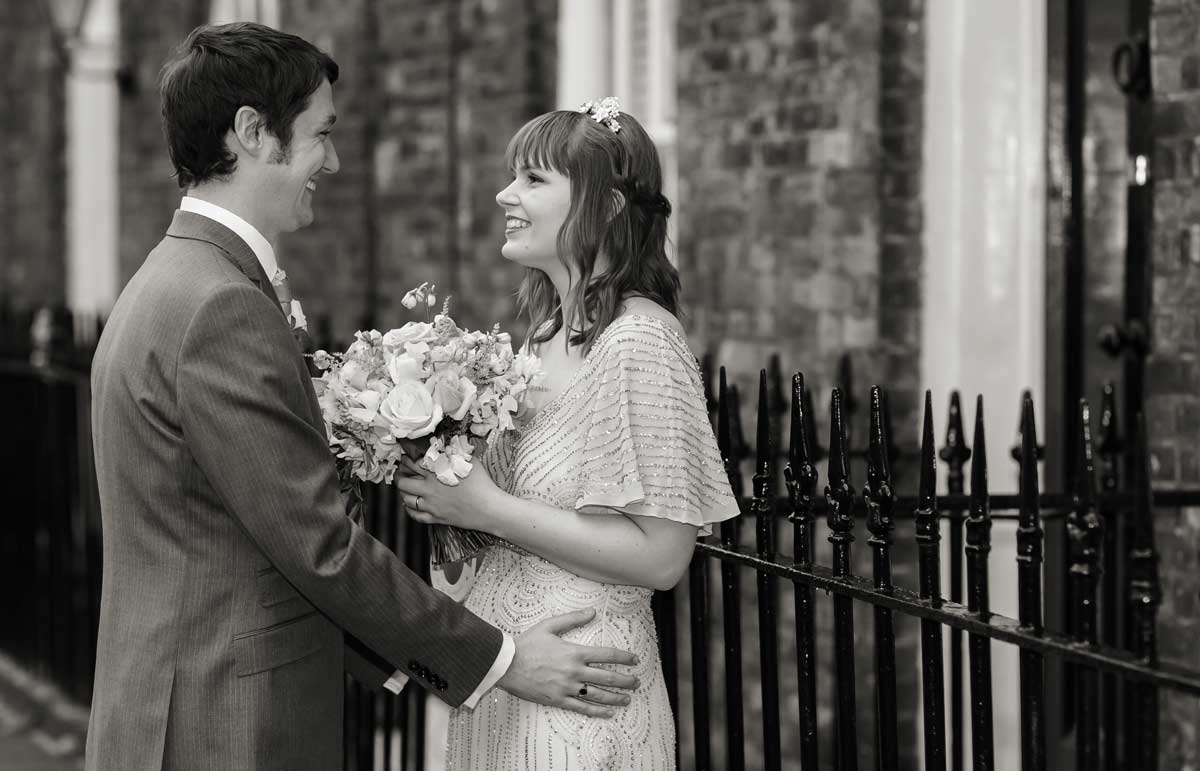 bride and groom laugh by Clerkenwell railings London