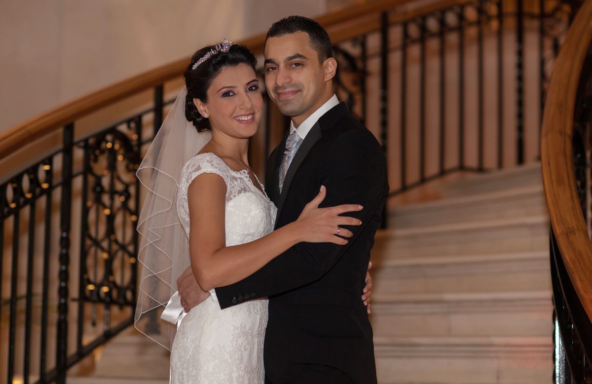 smiling wedding couple pose on white steps at Landmark Hotel