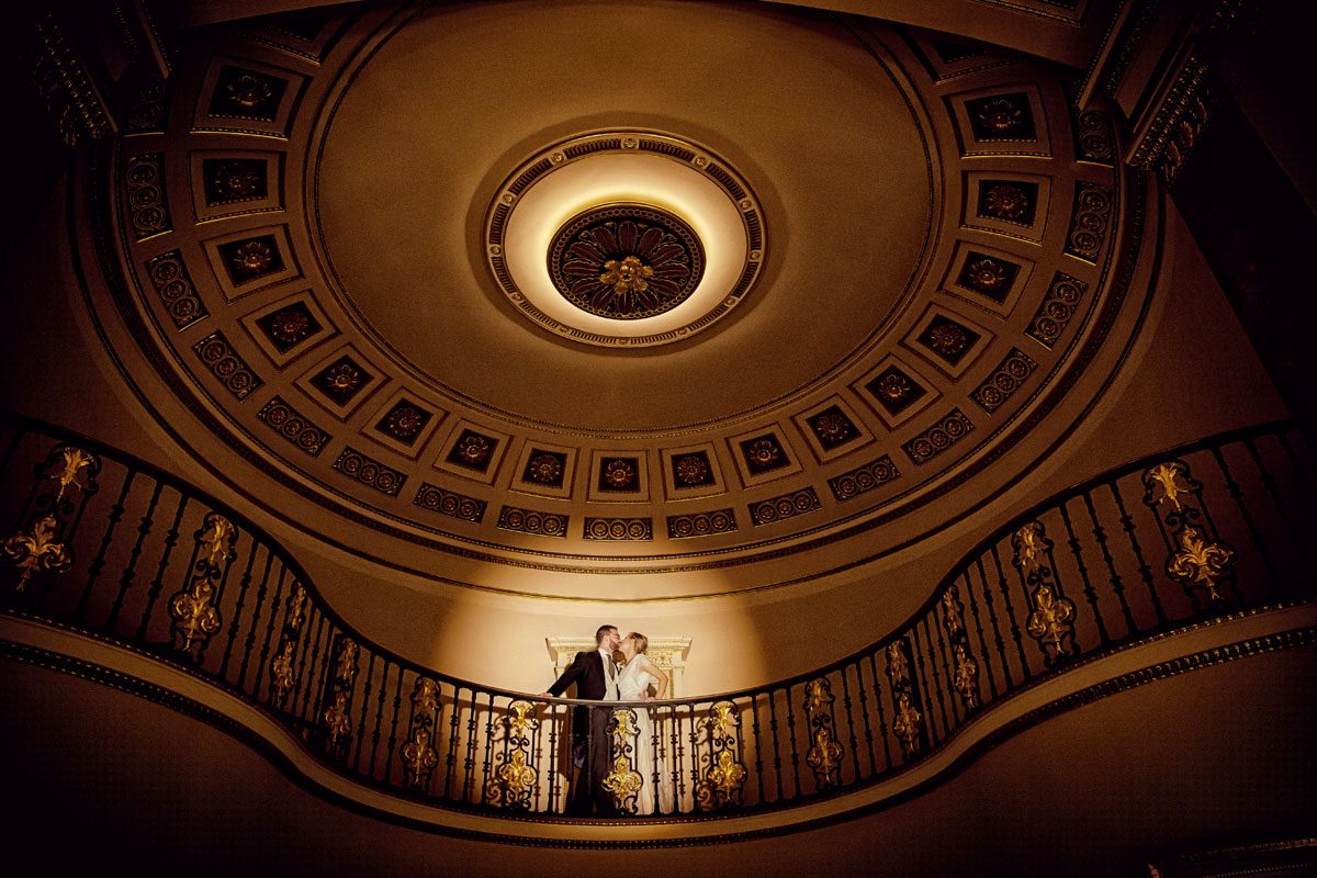 Lansdowne Club wedding photographers kiss in ballroom spotlight