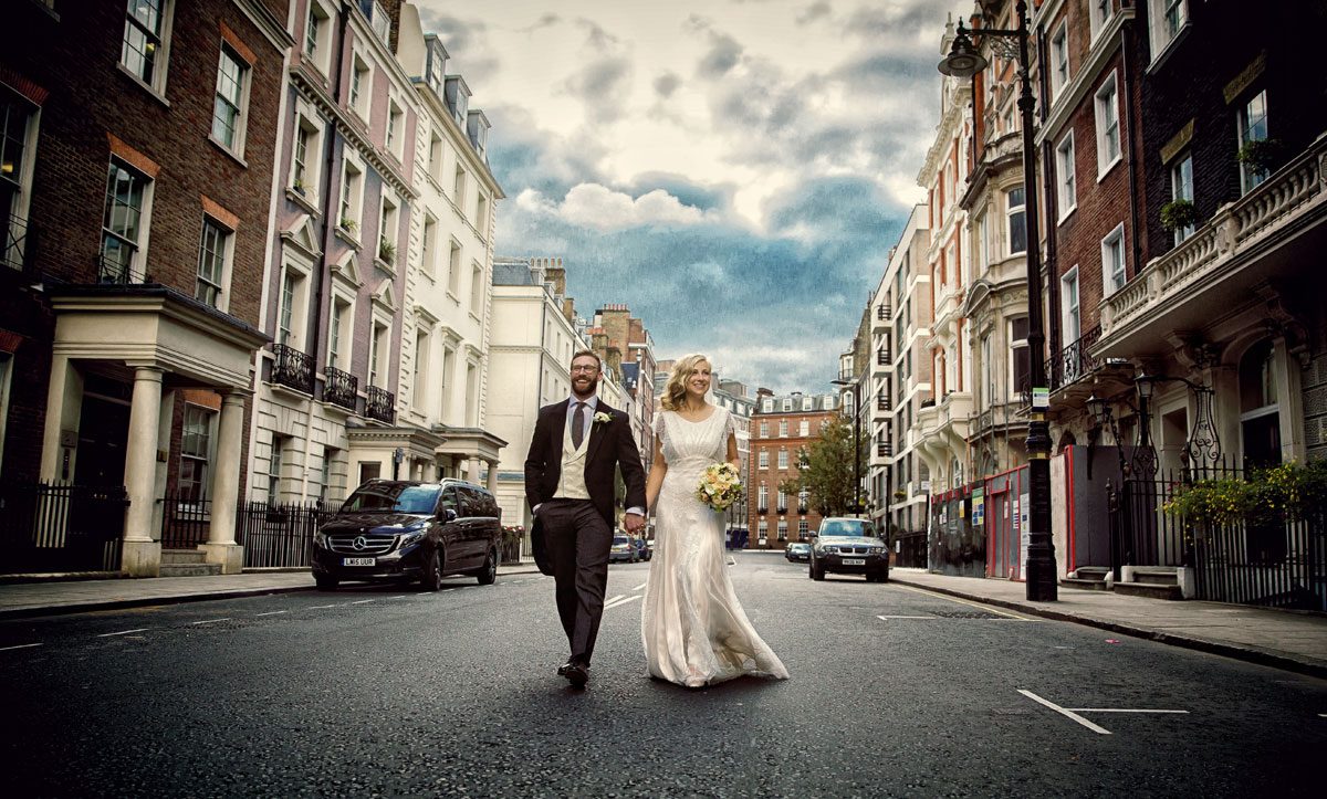 Wedding couple walk in middle of road in Mayfair London