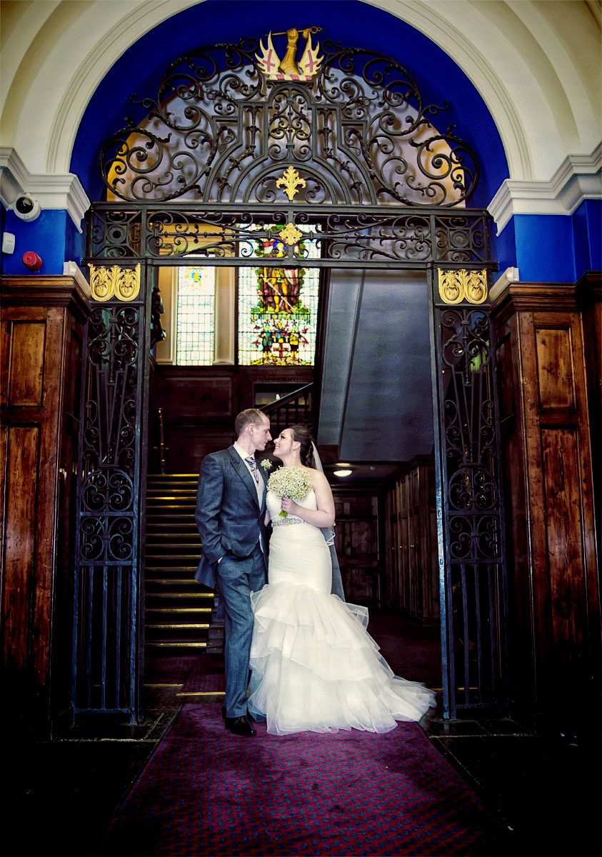 Wedding couple stand in arch at Armoury House wedding