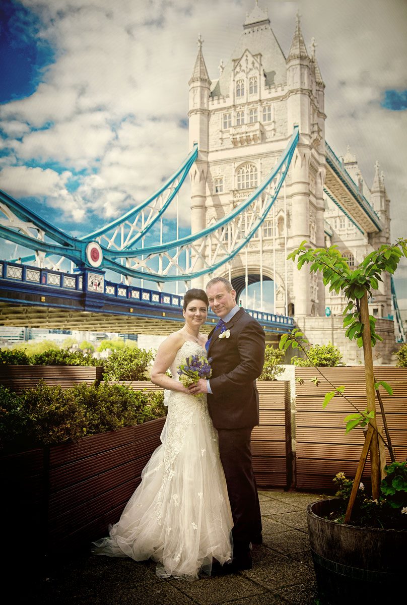 London wedding couple pose for photo by Tower Bridge