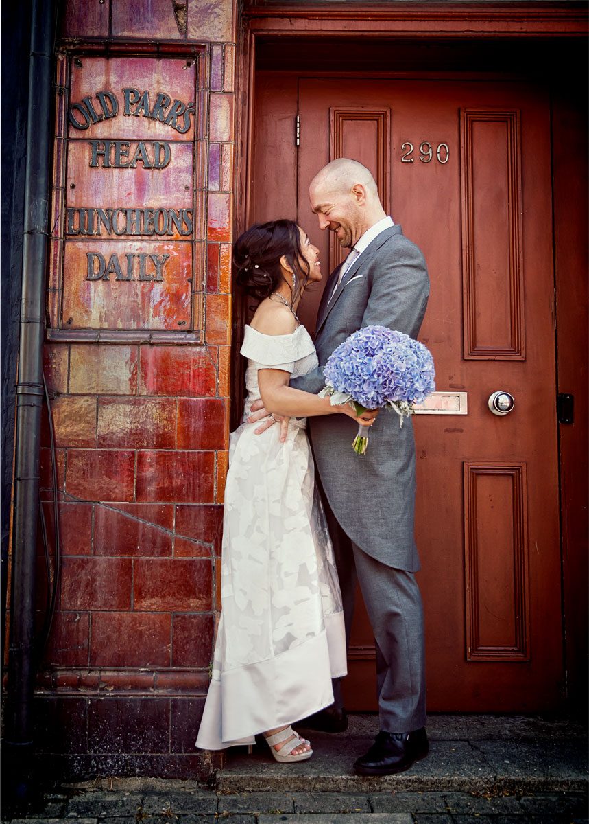 Couple hug in ornage doorway after Islington Town Hall wedding day