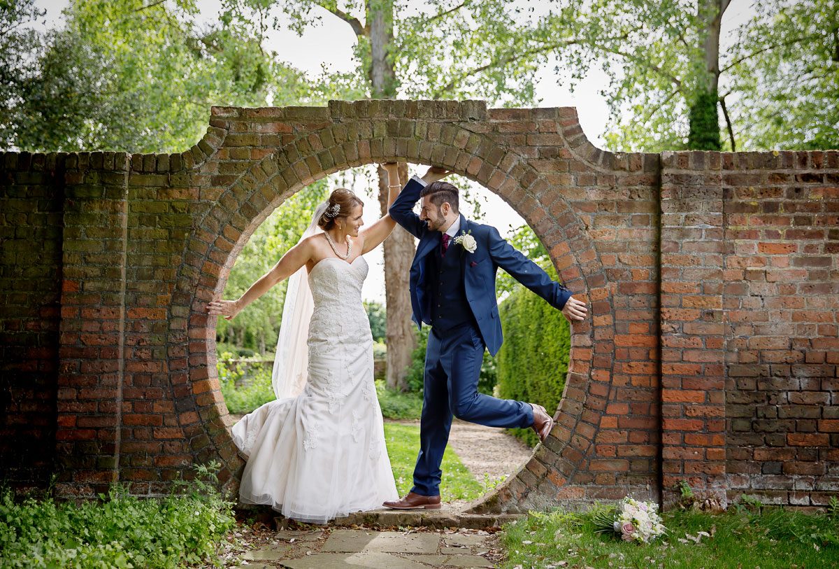 Wedding couple pose in hole in wall at Fanhams Hall