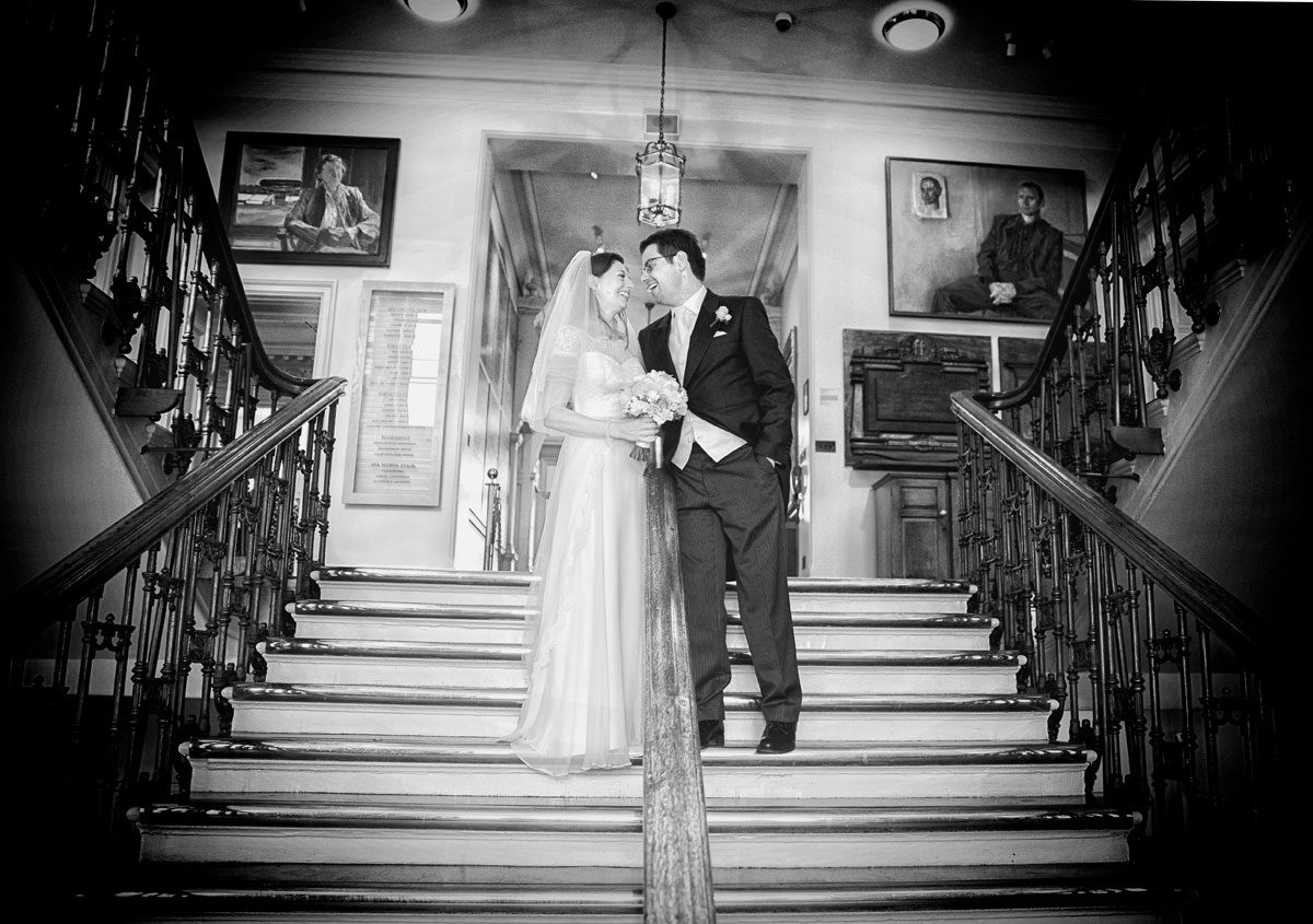 Bride and groom laughing on stairs at Lords Cricket Ground wedding day