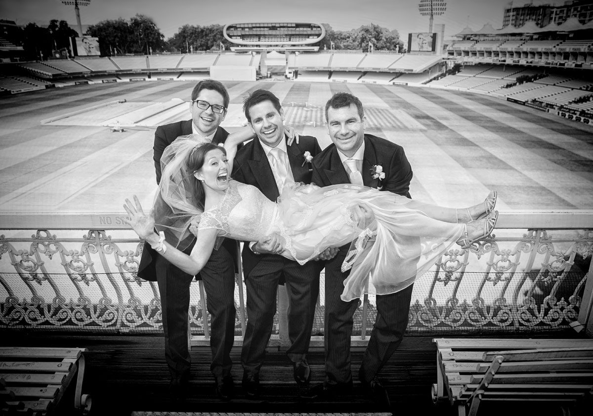 Groomsmen hold bride in stands at Lords Cricket Ground wedding