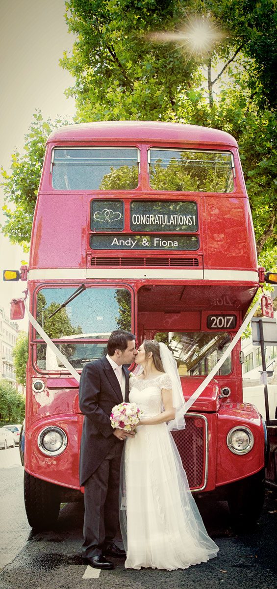 Kissing by London red bus at Lords cricket ground wedding