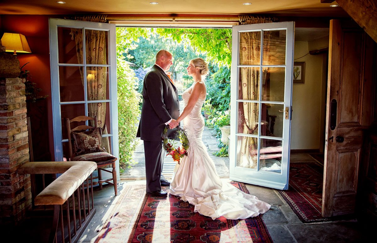 Couple hold hands at South Farm wedding in sunlit doorway