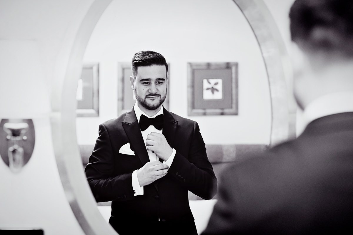 Groom gets ready in mirror for Connaught Rooms London wedding day
