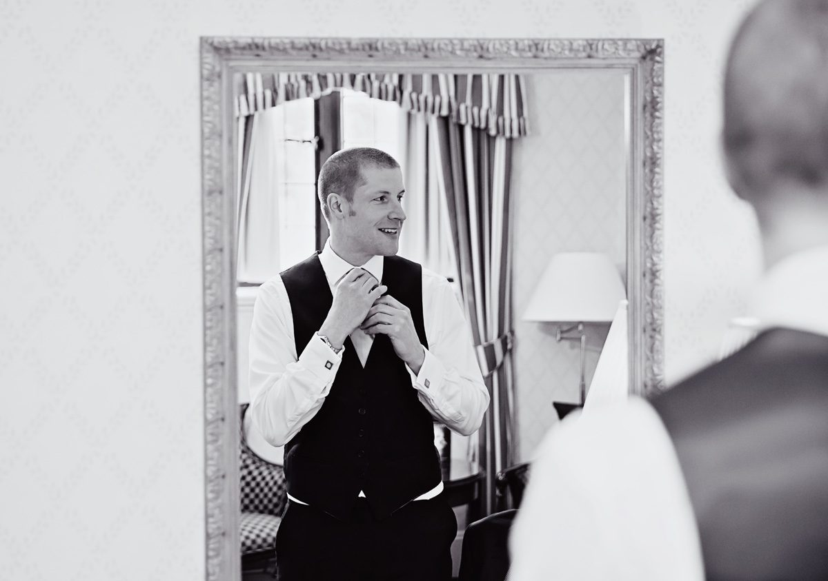 Groom gets ready in mirror for Hanbury Manor wedding