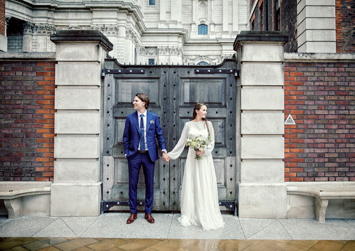 Central London wedding couple hold hands by St Pauls wooden gate