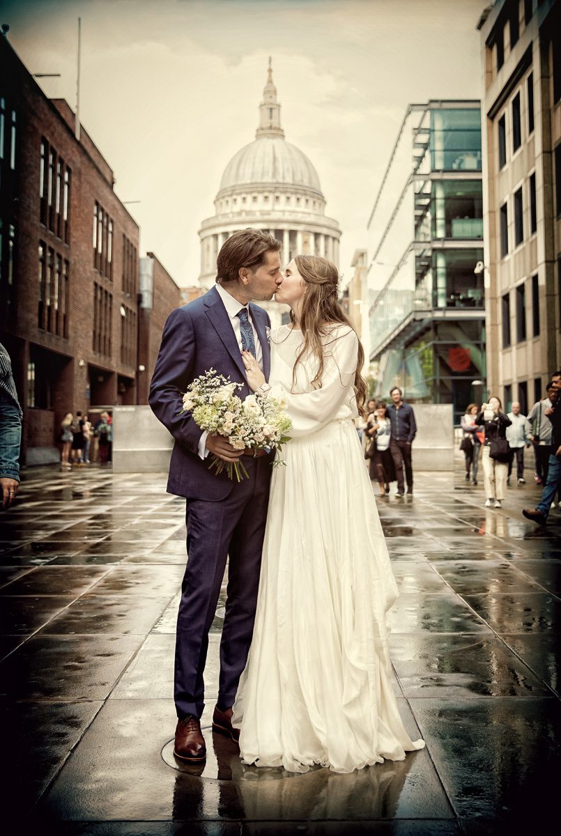 London wedding couple kiss in rain by St Pauls Cathedral