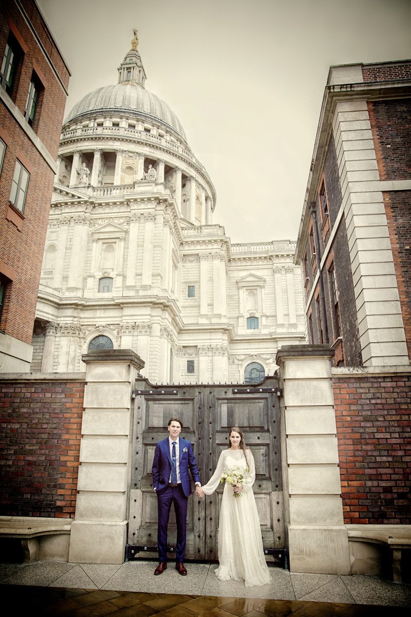 Wedding couple hold hands in Paternoster Square by St Pauls