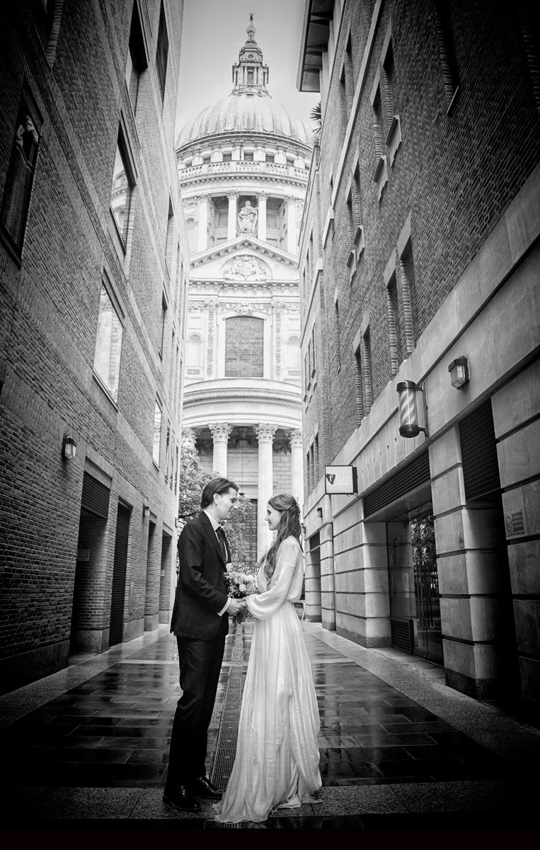Wedidng couple hold hamds in front of St pauls Cathedral London