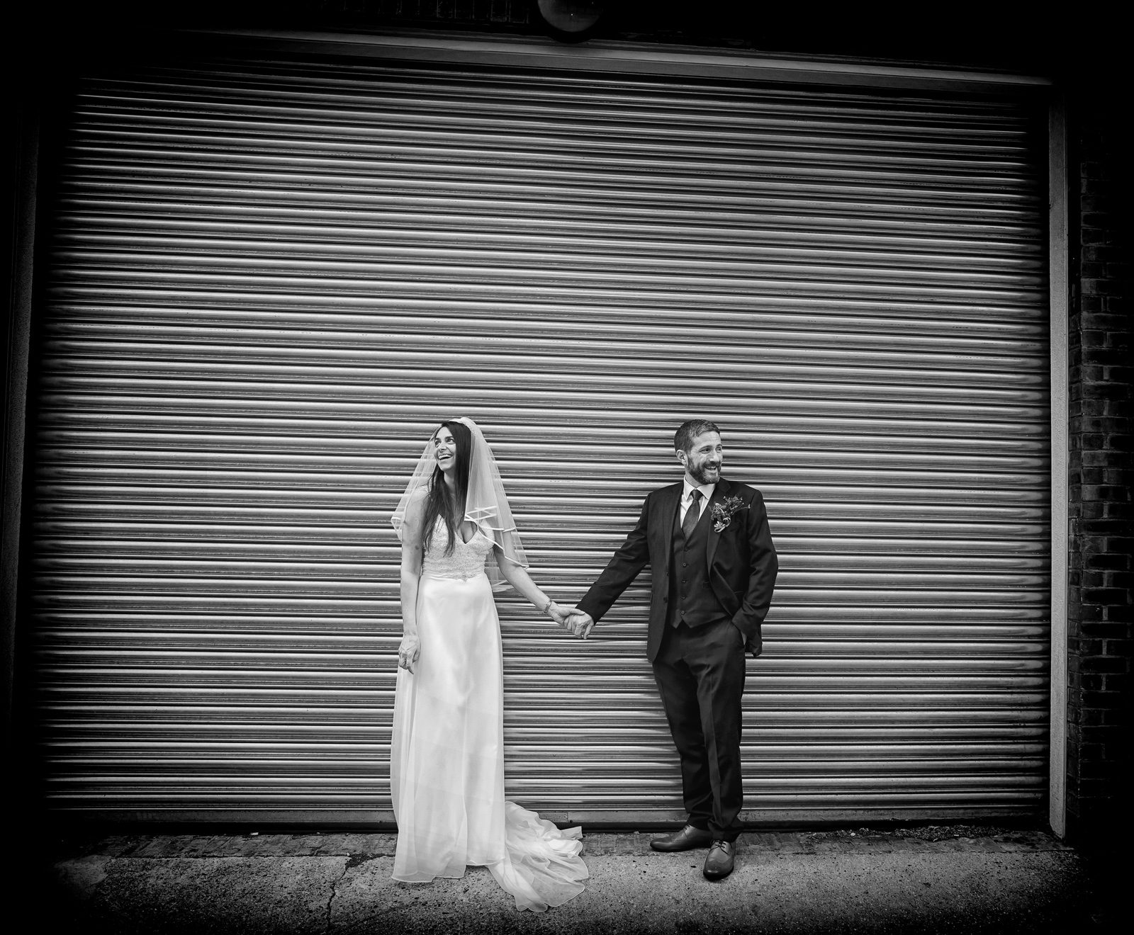 Bride and groom hold hands by roller doors Old Marylebone Town Hall