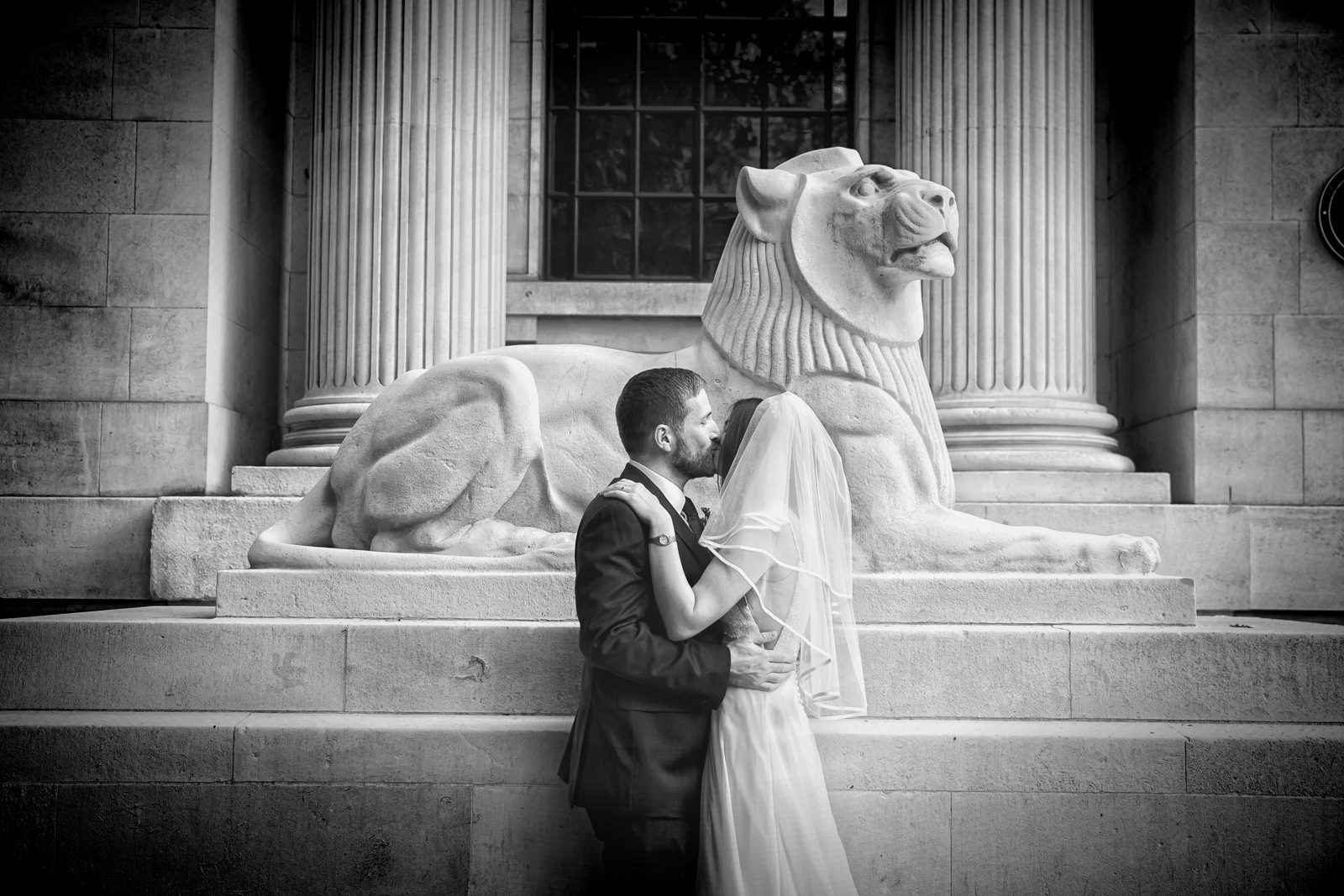 Bride and groom kiss by lion statue Old Marylebone Town Hall wedding