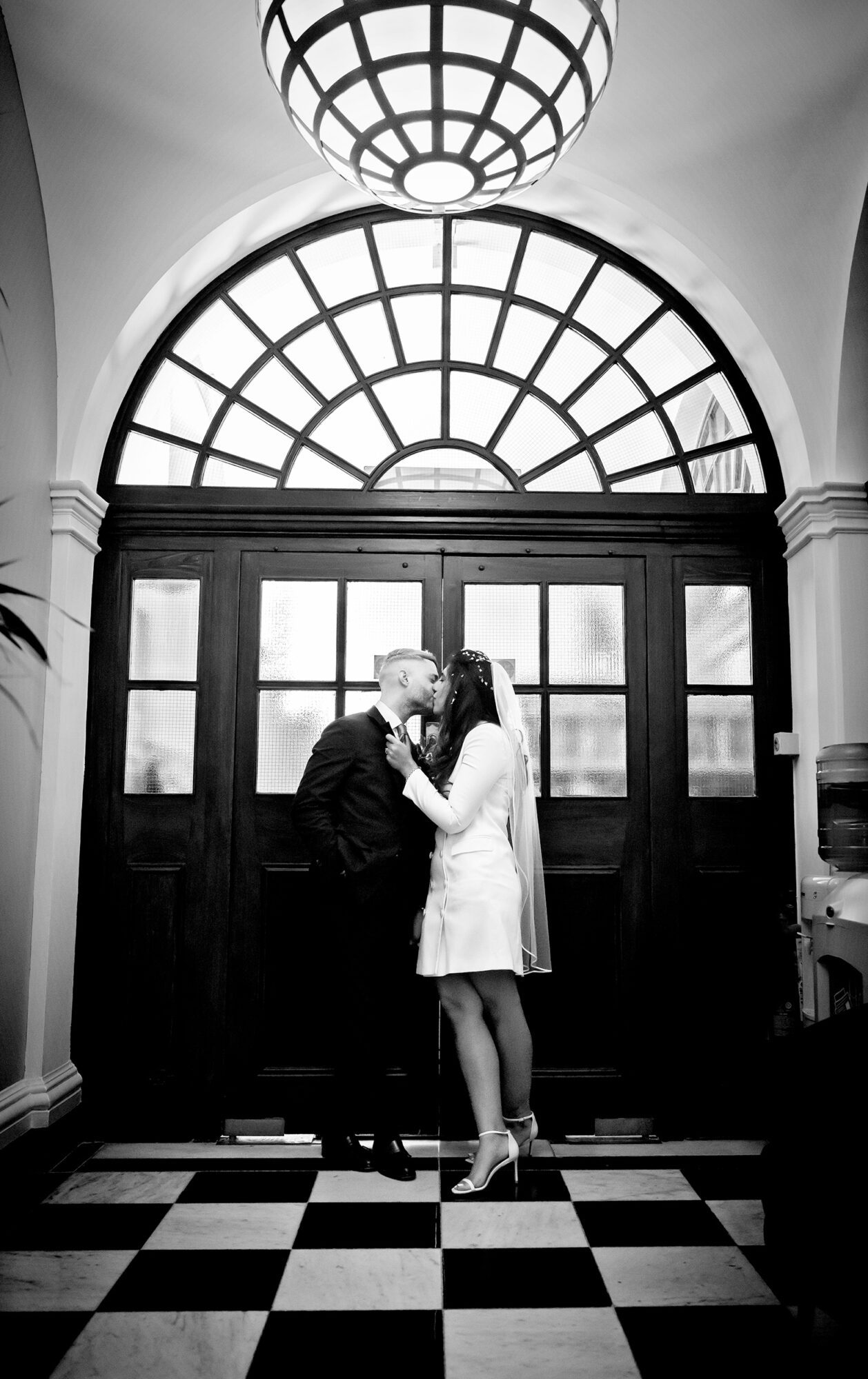 Bride and groom kiss by doors at Chelsea Old Town Hall wedding