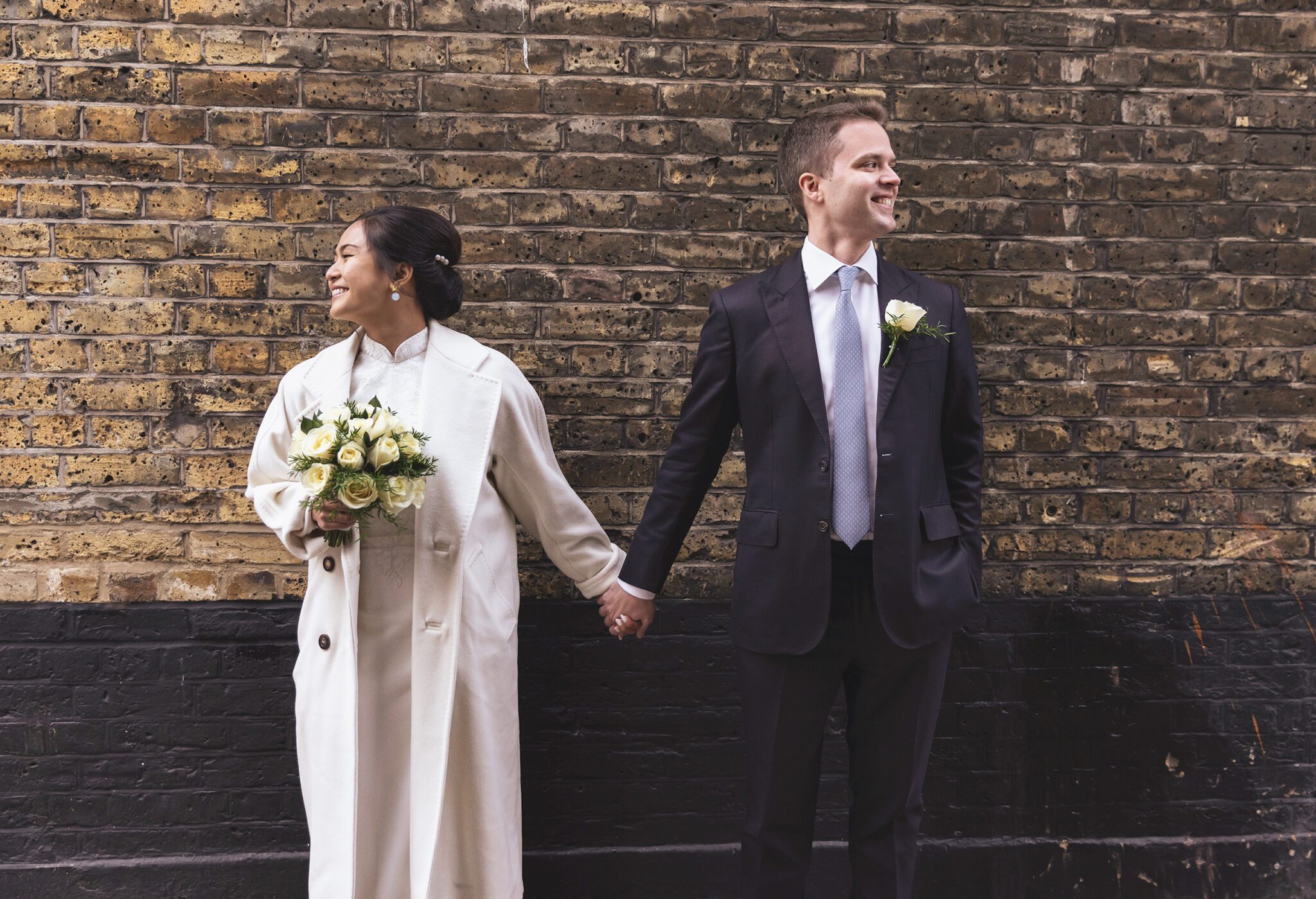 Old Marylebone Town Hall bride and groom hold hands by wall